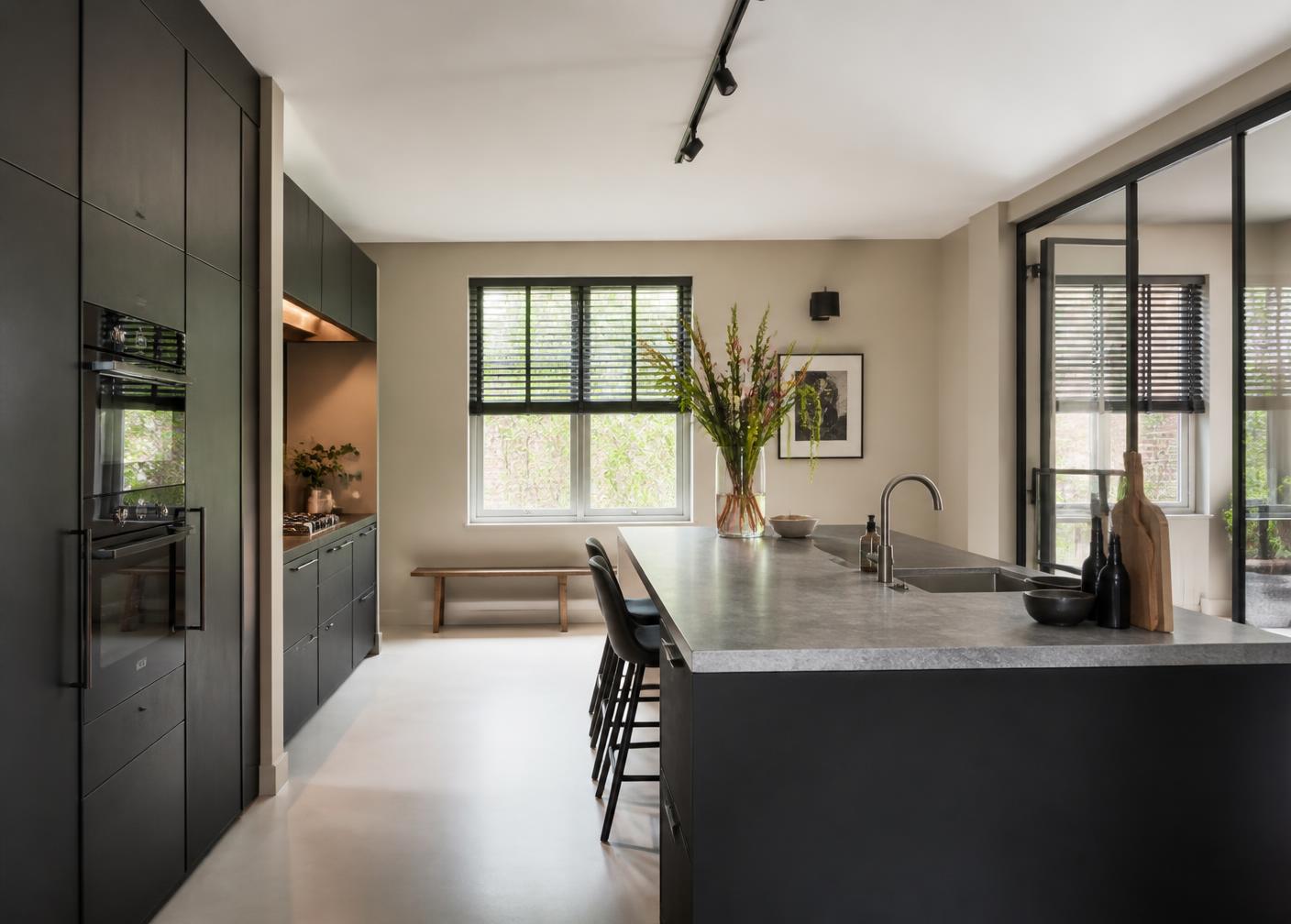 Moderne gerenoveerde keuken met matte donkere kastenwand en stenen werkblad